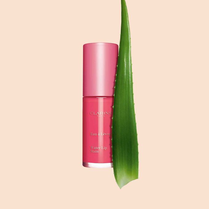 Packshot of the new pink lip stain from Clarins next to an aloe vera plant on a white background