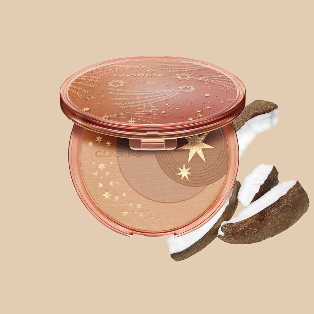 Packshot of the bronzing compact powder from Clarins, displayed alongside slices of coconut on a white background